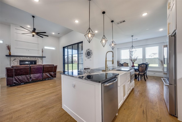 145 Chisolm Trl, Pottsboro, TX 75076 - kitchen featuring stainless steel appliances, light wood-style flooring, white cabinets, a brick fireplace, and dark stone countertops