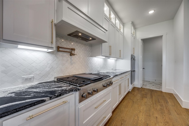 145 Chisolm Trl, Pottsboro, TX 75076 - kitchen with custom exhaust hood, stainless steel gas stovetop, white cabinets, glass insert cabinets, and dark stone counters
