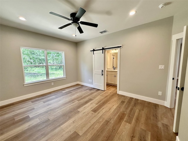 913 Carter, Sulphur Springs, TX 75482 - unfurnished bedroom with a barn door, light wood-style floors, baseboards, recessed lighting, and ensuite bath