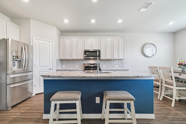 1904 Tomahawk Trl, Aubrey, TX 76227 - kitchen featuring appliances with stainless steel finishes, dark wood-type flooring, a kitchen bar, and recessed lighting