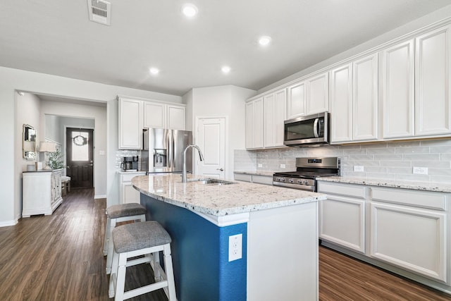 1904 Tomahawk Trl, Aubrey, TX 76227 - kitchen with appliances with stainless steel finishes, a sink, a breakfast bar area, dark wood finished floors, and decorative backsplash