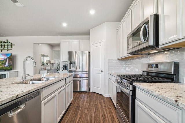 1904 Tomahawk Trl, Aubrey, TX 76227 - kitchen featuring appliances with stainless steel finishes, a sink, dark wood-style flooring, white cabinets, and light stone counters