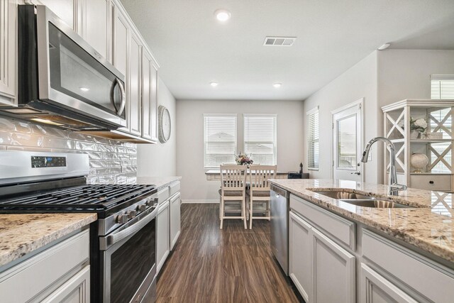 1904 Tomahawk Trl, Aubrey, TX 76227 - kitchen featuring stainless steel appliances, a sink, dark wood-style floors, tasteful backsplash, and baseboards