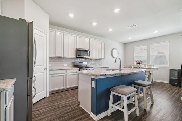 1904 Tomahawk Trl, Aubrey, TX 76227 - kitchen featuring stainless steel appliances, a sink, dark wood-type flooring, tasteful backsplash, and a kitchen bar