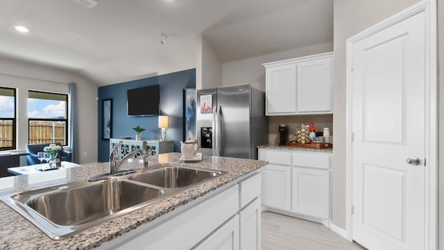 509 Marsh St, Cleburne, TX 76033 - kitchen featuring stainless steel fridge with ice dispenser, a sink, white cabinetry, lofted ceiling, and light stone countertops