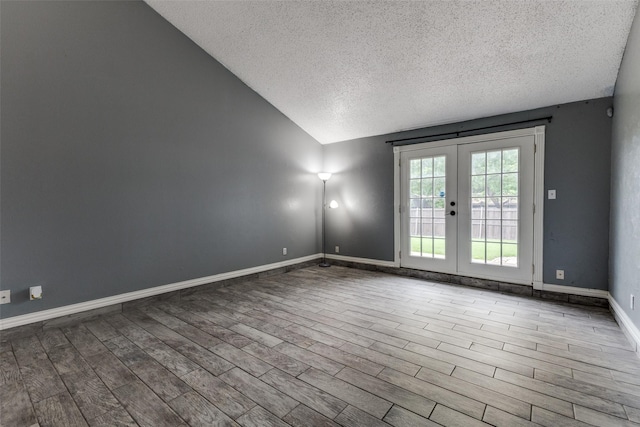 2929 Forest Park Dr, Garland, TX 75040 - spare room featuring a textured ceiling, french doors, lofted ceiling, wood finished floors, and baseboards