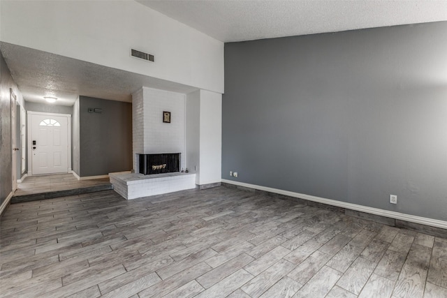 2929 Forest Park Dr, Garland, TX 75040 - unfurnished living room featuring wood finished floors, a textured ceiling, baseboards, and a fireplace