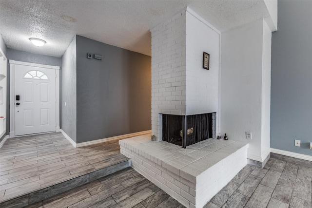 2929 Forest Park Dr, Garland, TX 75040 - foyer featuring a textured ceiling, wood finished floors, a fireplace, and baseboards