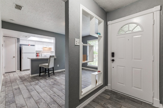 2929 Forest Park Dr, Garland, TX 75040 - entryway featuring a textured ceiling, wood finished floors, and baseboards