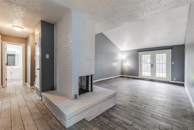 2929 Forest Park Dr, Garland, TX 75040 - unfurnished living room with a textured ceiling, wood finished floors, french doors, lofted ceiling, and a fireplace