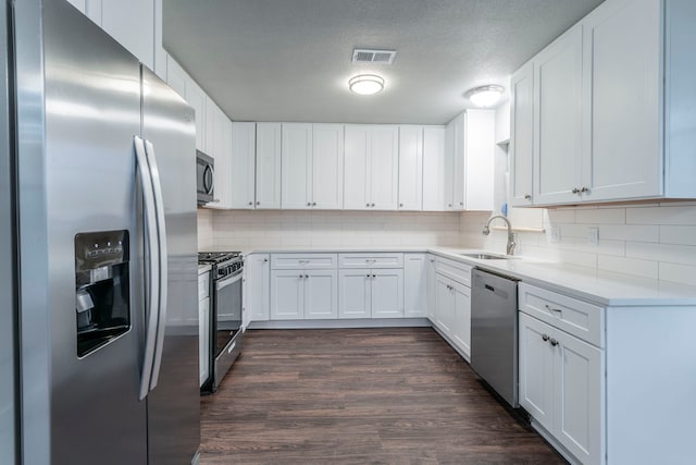 1725 Camara Ct, Grand Prairie, TX 75051 - kitchen with stainless steel appliances, a sink, tasteful backsplash, dark wood finished floors, and white cabinetry