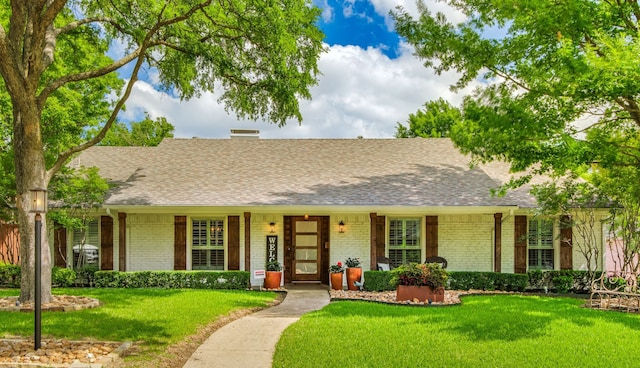 ranch-style house featuring brick siding, roof with shingles, and a front lawn