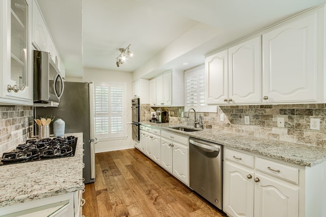 kitchen featuring black appliances, a sink, white cabinetry, and decorative backsplash