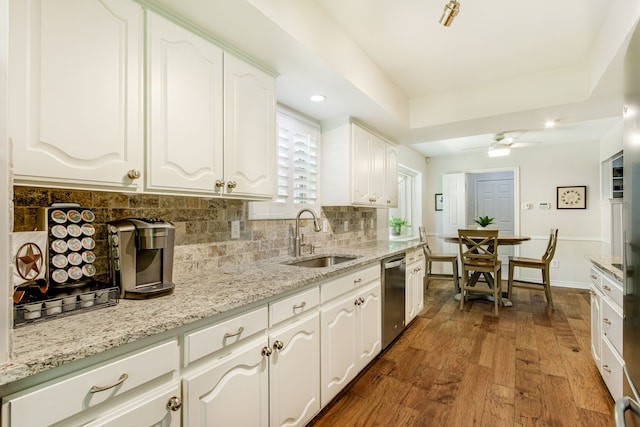 kitchen with a sink, dishwasher, dark wood finished floors, white cabinets, and tasteful backsplash