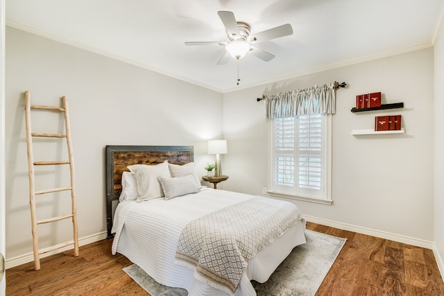 bedroom with crown molding, baseboards, wood finished floors, and ceiling fan
