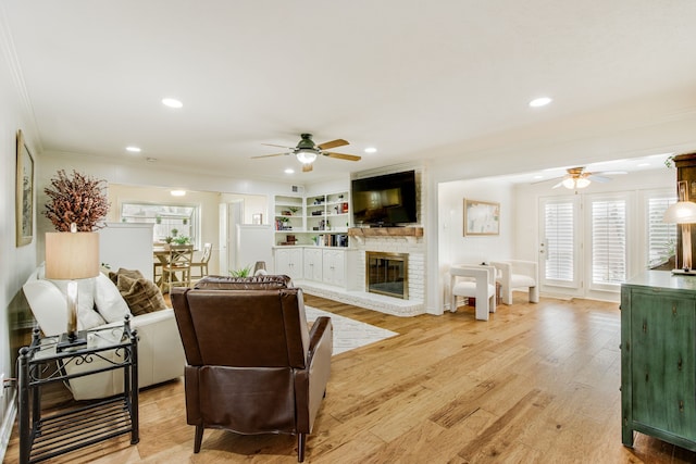 living area with ceiling fan, crown molding, a fireplace, light wood-style floors, and recessed lighting