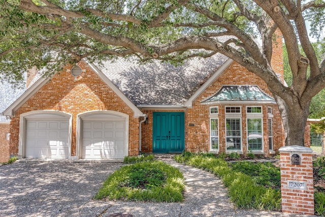 7207 Abrams Place Ct, Dallas, TX 75231 - english style home featuring brick siding, an attached garage, a chimney, and driveway