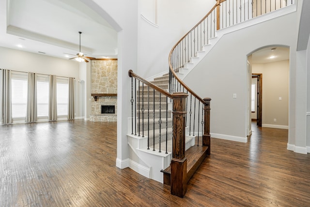 713 Calm Crest Dr, Rockwall, TX 75087 - stairway featuring ceiling fan, wood finished floors, a high ceiling, a fireplace, and arched walkways