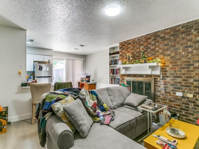 508 Billie Ruth Ln, Hurst, TX 76053 - living room featuring baseboards, a textured ceiling, wood finished floors, a fireplace, and brick wall