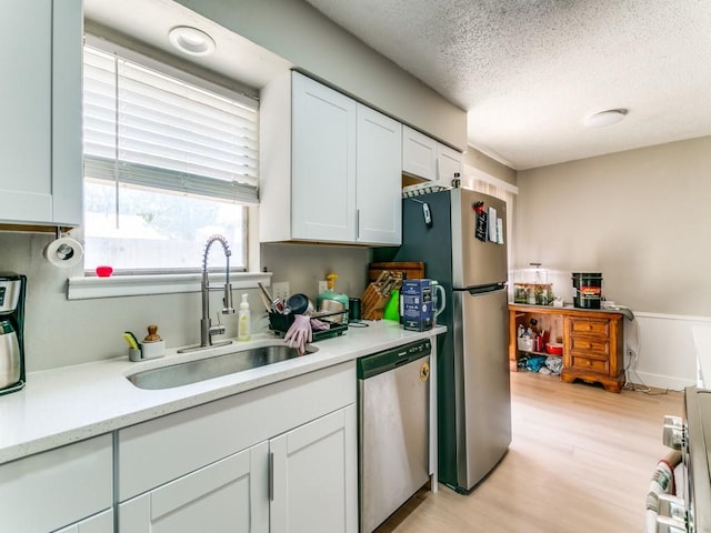 508 Billie Ruth Ln, Hurst, TX 76053 - kitchen featuring appliances with stainless steel finishes, a sink, light countertops, a textured ceiling, and white cabinetry