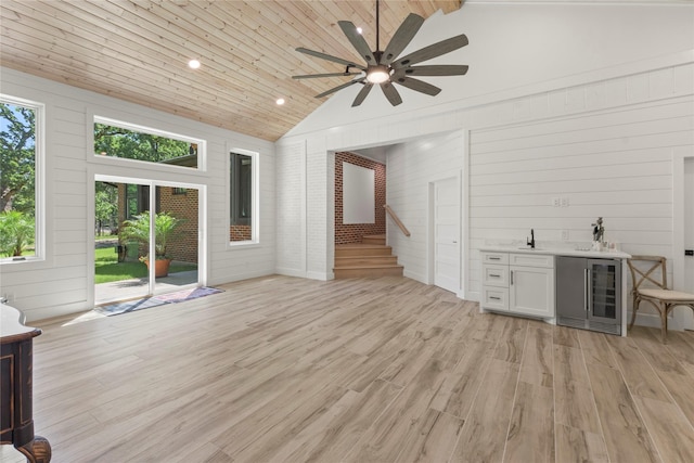 401 Tangle Dr, Tool, TX 75143 - unfurnished living room featuring beverage cooler, bar with sink, ceiling fan, stairs, and light wood-style floors