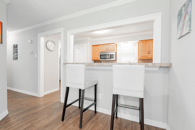 7510 County Road 118, Kaufman, TX 75142 - kitchen with stainless steel microwave, light brown cabinetry, light wood-style flooring, light countertops, and ornamental molding