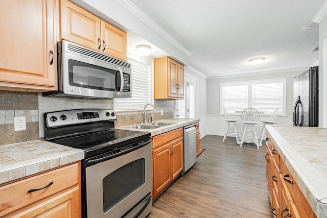 7510 County Road 118, Kaufman, TX 75142 - kitchen with stainless steel appliances, tile countertops, a sink, wood finished floors, and crown molding