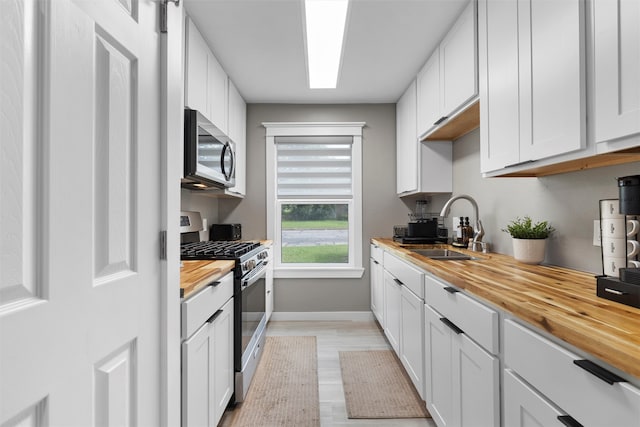 1900 N 15th St, Waco, TX 76707 - kitchen featuring stainless steel appliances, wood counters, a sink, baseboards, and white cabinetry