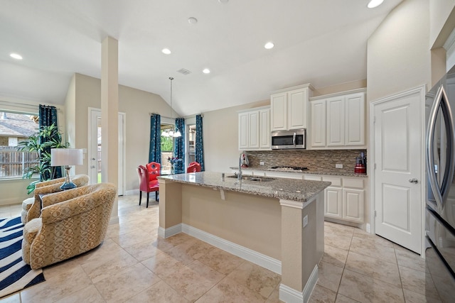 1109 Hot Springs Way, Celina, TX 75009 - kitchen with a sink, stainless steel appliances, vaulted ceiling, light stone countertops, and an island with sink