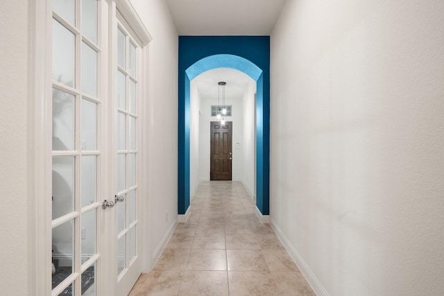 1109 Hot Springs Way, Celina, TX 75009 - hallway featuring french doors, arched walkways, light tile patterned floors, and baseboards