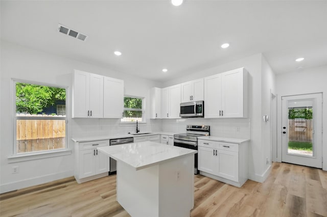 2927 Valentine St, Dallas, TX 75215 - kitchen featuring appliances with stainless steel finishes, a sink, backsplash, a center island, and white cabinetry