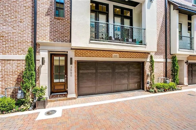 3660 Belvedere Ct, Dallas, TX 75219 - doorway to property featuring brick siding, an attached garage, decorative driveway, and a balcony