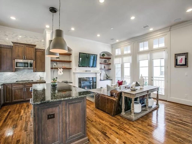 3660 Belvedere Ct, Dallas, TX 75219 - kitchen with appliances with stainless steel finishes, dark wood-type flooring, dark stone counters, a kitchen island, and recessed lighting