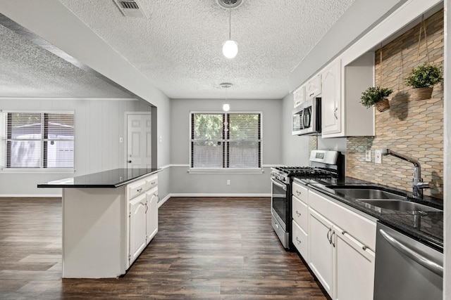 1530 Lime Leaf Ln, Duncanville, TX 75137 - kitchen featuring appliances with stainless steel finishes, a sink, dark countertops, a textured ceiling, and dark wood-type flooring