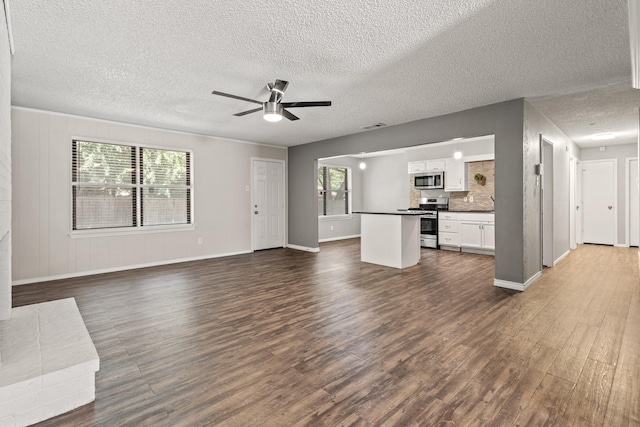 1530 Lime Leaf Ln, Duncanville, TX 75137 - unfurnished living room with dark wood-type flooring, a textured ceiling, baseboards, and a ceiling fan