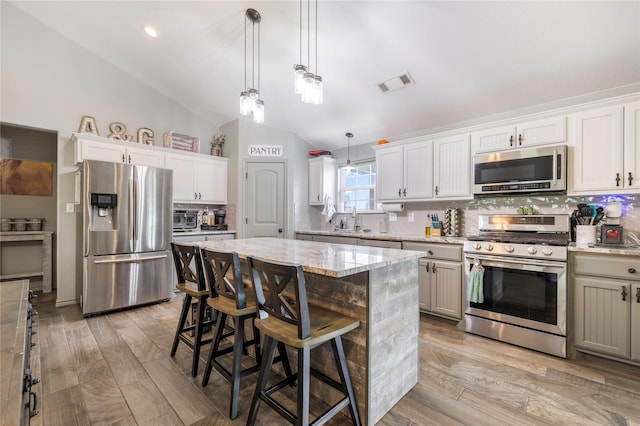 1668 Poe Prairie Rd, Millsap, TX 76066 - kitchen featuring stainless steel appliances, decorative backsplash, lofted ceiling, a sink, and light stone countertops