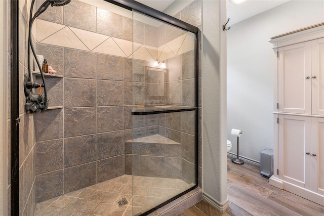 1668 Poe Prairie Rd, Millsap, TX 76066 - bathroom featuring wood finished floors, a stall shower, baseboards, and toilet