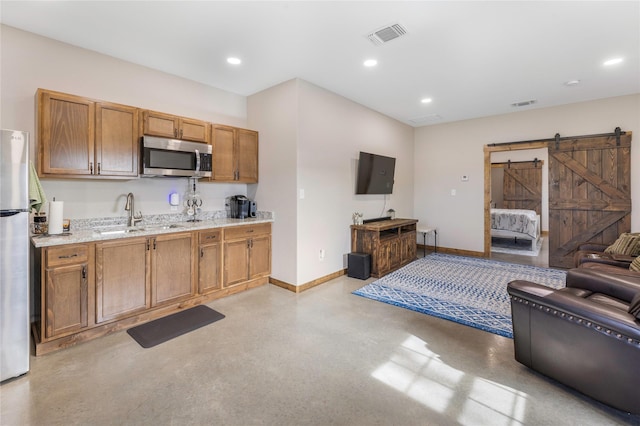 1668 Poe Prairie Rd, Millsap, TX 76066 - kitchen featuring appliances with stainless steel finishes, a barn door, a sink, open floor plan, and baseboards