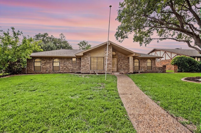 view of front of house with a front lawn, brick siding, and roof with shingles