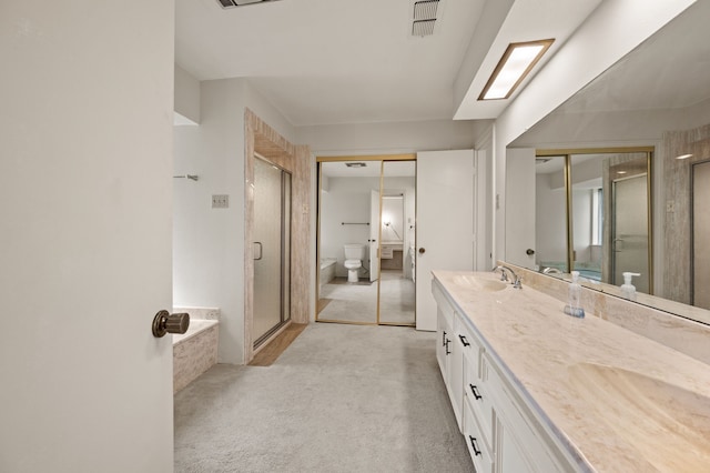 bathroom with a stall shower, double vanity, a tub, and toilet