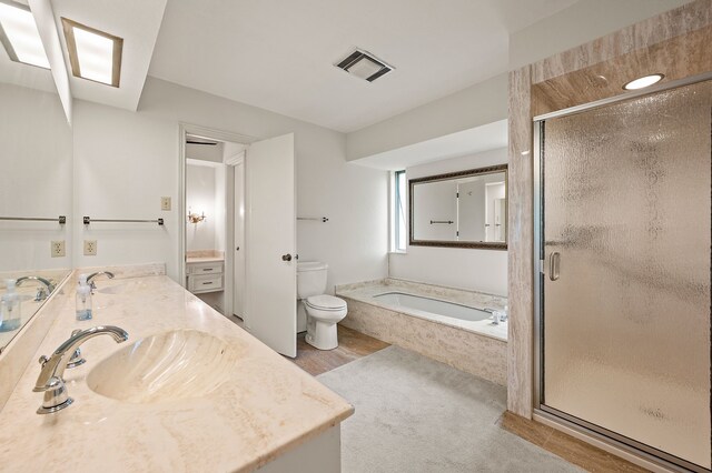 full bathroom with a bath, toilet, a shower stall, and double vanity