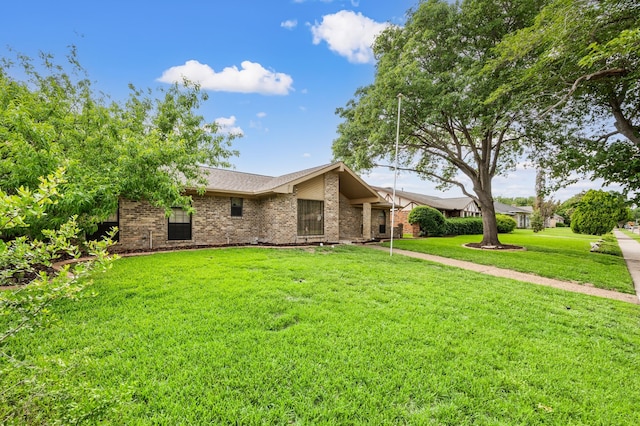 view of front of home with brick siding, a front lawn, and a shingled roof