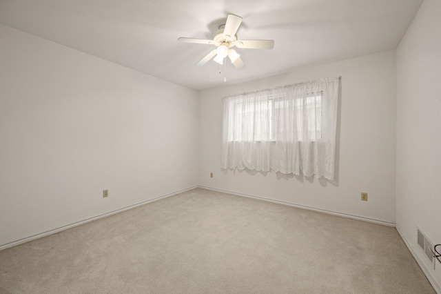 carpeted spare room with a ceiling fan and baseboards