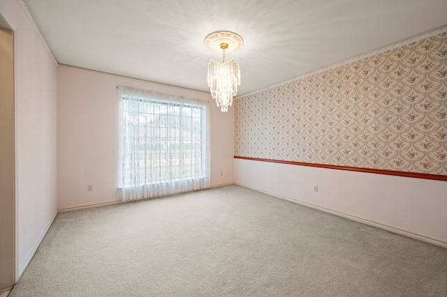 carpeted empty room featuring a chandelier and baseboards