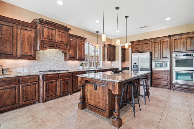 801 Shadow Hill Dr, Prosper, TX 75078 - kitchen featuring appliances with stainless steel finishes, a sink, a breakfast bar, tasteful backsplash, and a kitchen island