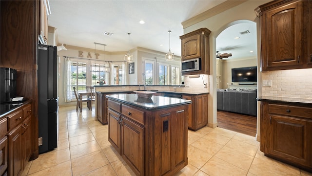 12046 Erin Ln, Fort Worth, TX 76179 - kitchen with a peninsula, stainless steel microwave, crown molding, tasteful backsplash, and light tile patterned floors