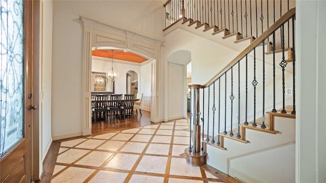 12046 Erin Ln, Fort Worth, TX 76179 - foyer featuring inlaid floor details, arched walkways, a towering ceiling, stairway, and baseboards