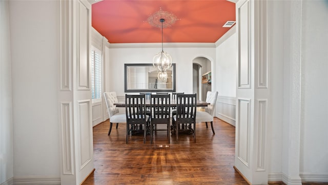 12046 Erin Ln, Fort Worth, TX 76179 - dining area with dark wood-type flooring, a decorative wall, arched walkways, wainscoting, and a chandelier