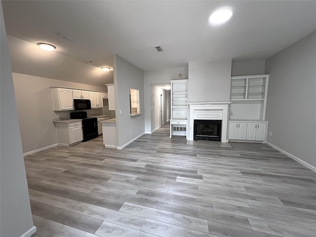 902 Mack Pl, Denton, TX 76209 - unfurnished living room featuring baseboards, light wood-style flooring, a fireplace with flush hearth, and lofted ceiling