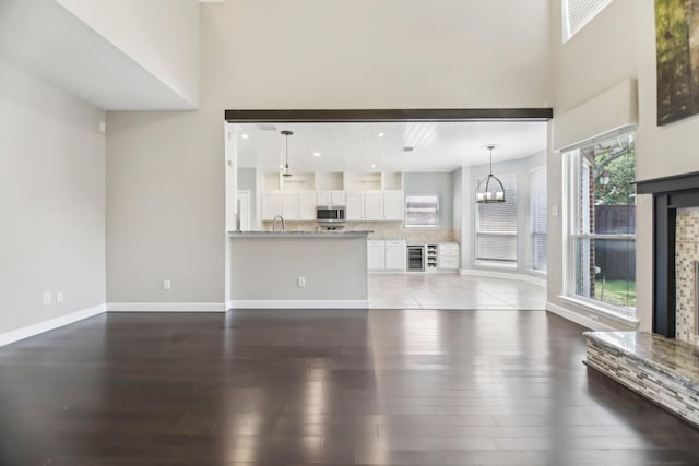 11003 Canoe Rd, Frisco, TX 75035 - unfurnished living room with wood finished floors, a chandelier, beverage cooler, a high ceiling, and baseboards